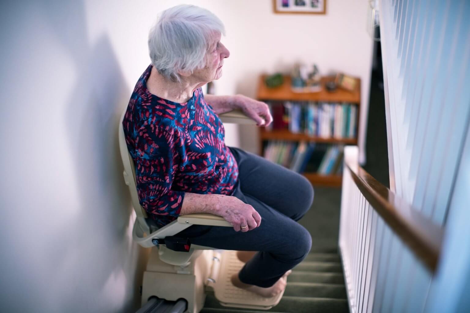Seniorin fährt entspannt mit dem Treppenlift nach oben